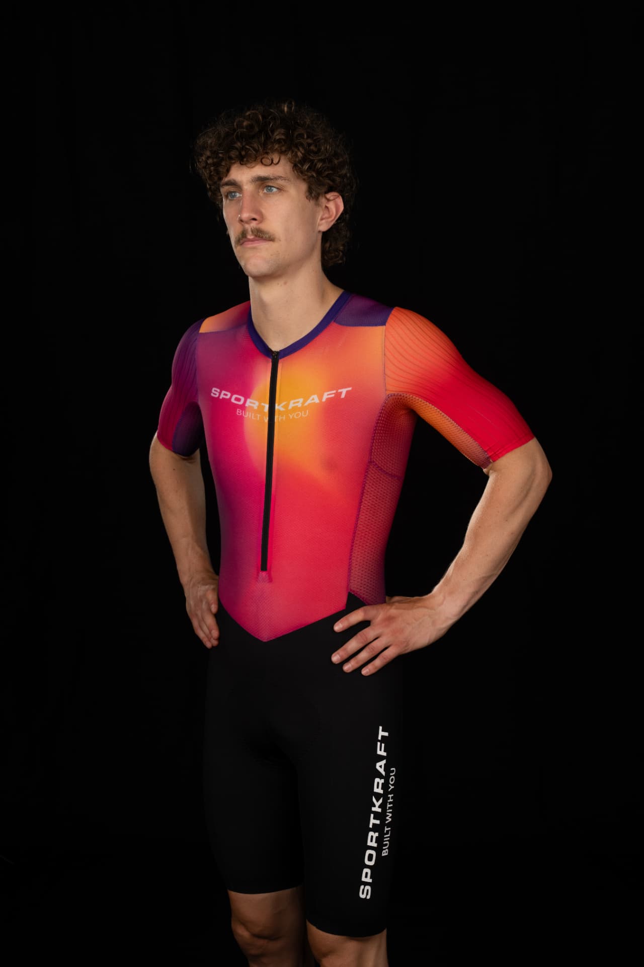 Rider in the SPORTKRAFT Race 2.4 Short Sleeve Race Suit in a pink, orange and purple gradient