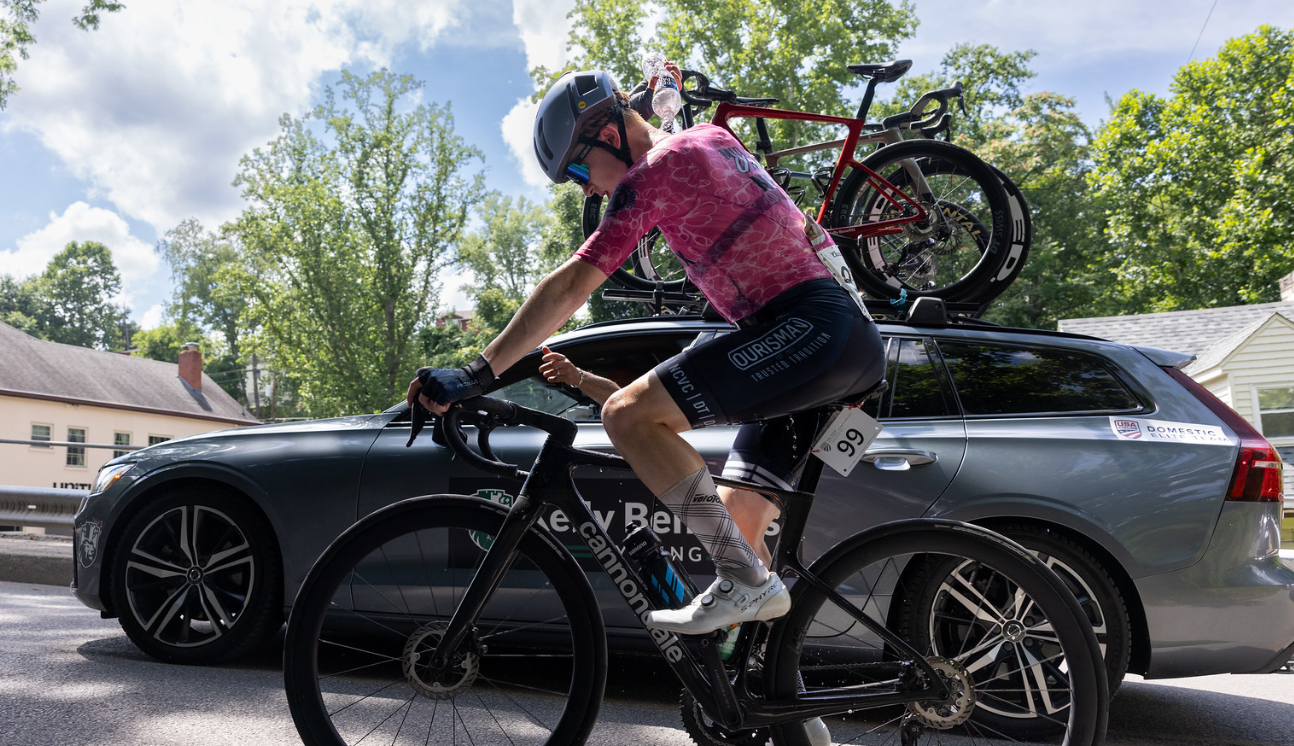 Rider taking a bottle beside the team car