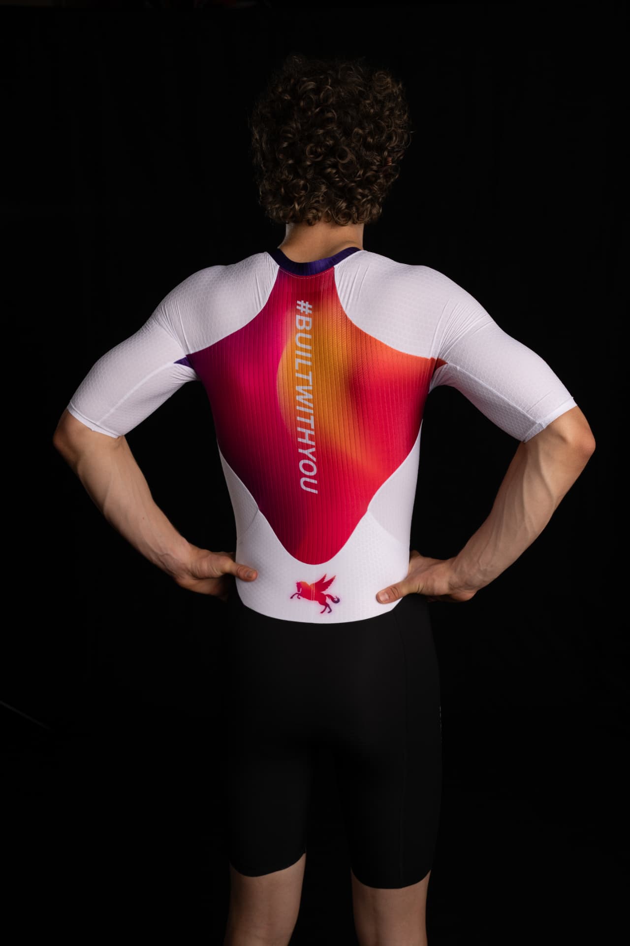 Back panel of a white and gradient SPORTKRAFT skinsuit with #BUILTWITHYOU print