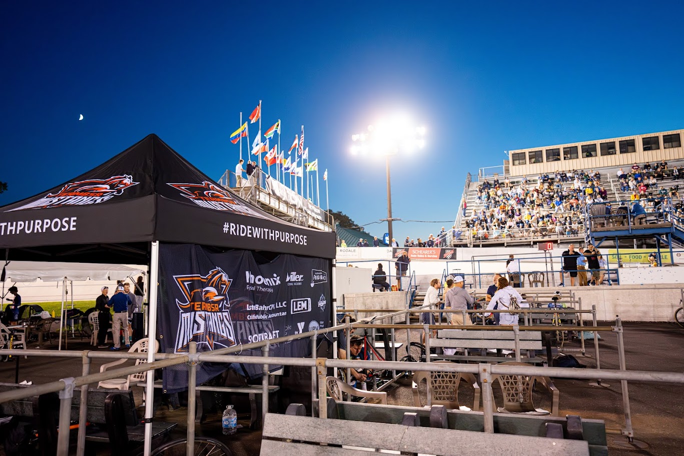 Branded team tent, banners and flags at a floodlit velodrome